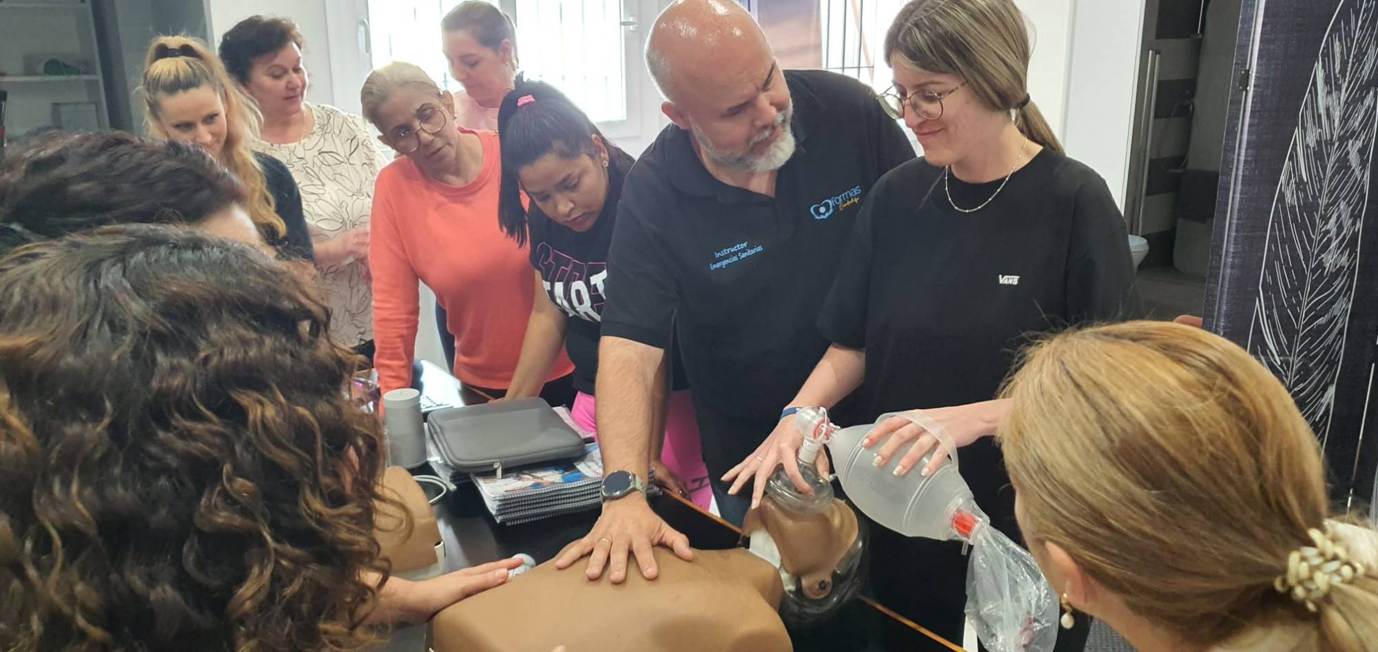 Instructor de Formas Cardiolife enseñando SVB con ambú y maniquí a un grupo de participantes